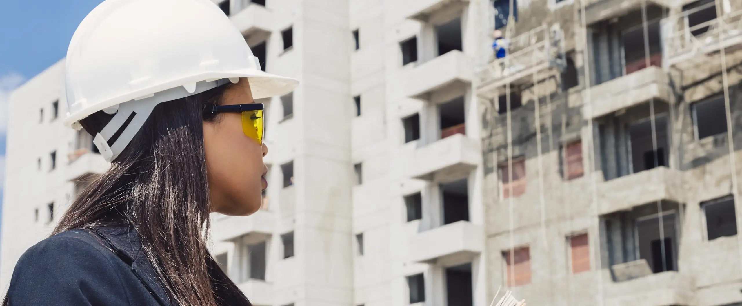 Personne portant un casque de chantier observant un immeuble en construction